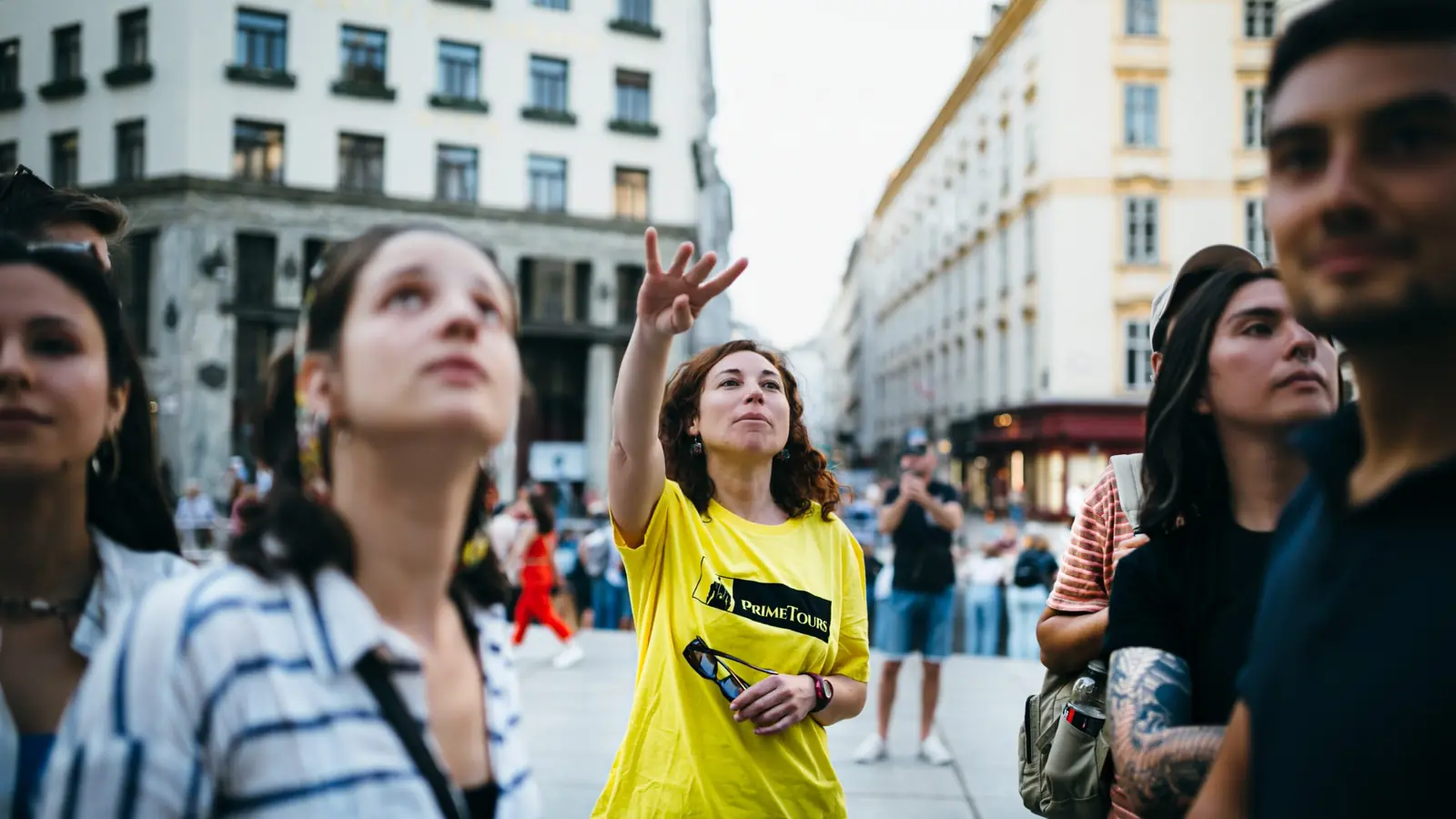 Prime Tours guide in a yellow shirt showing guests a building in Vienna's old town