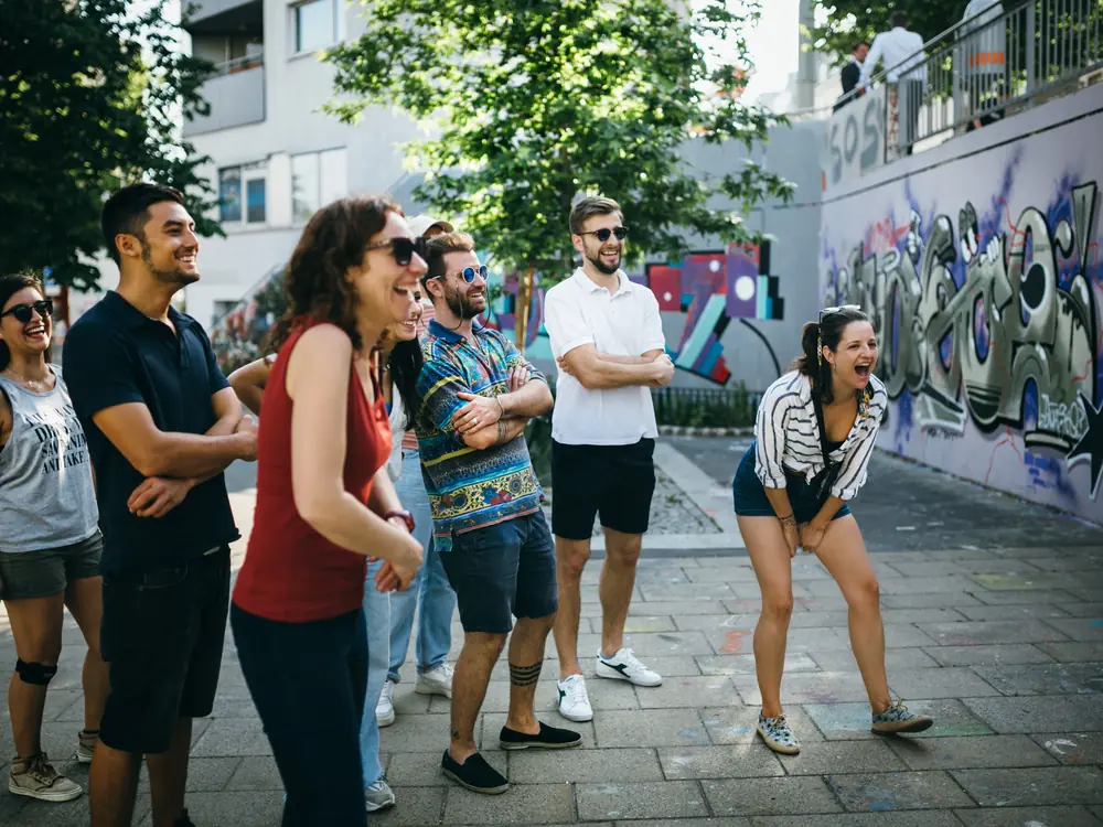 Large group laughing with their Prime Tours guide in front of a street-art wall in Vienna