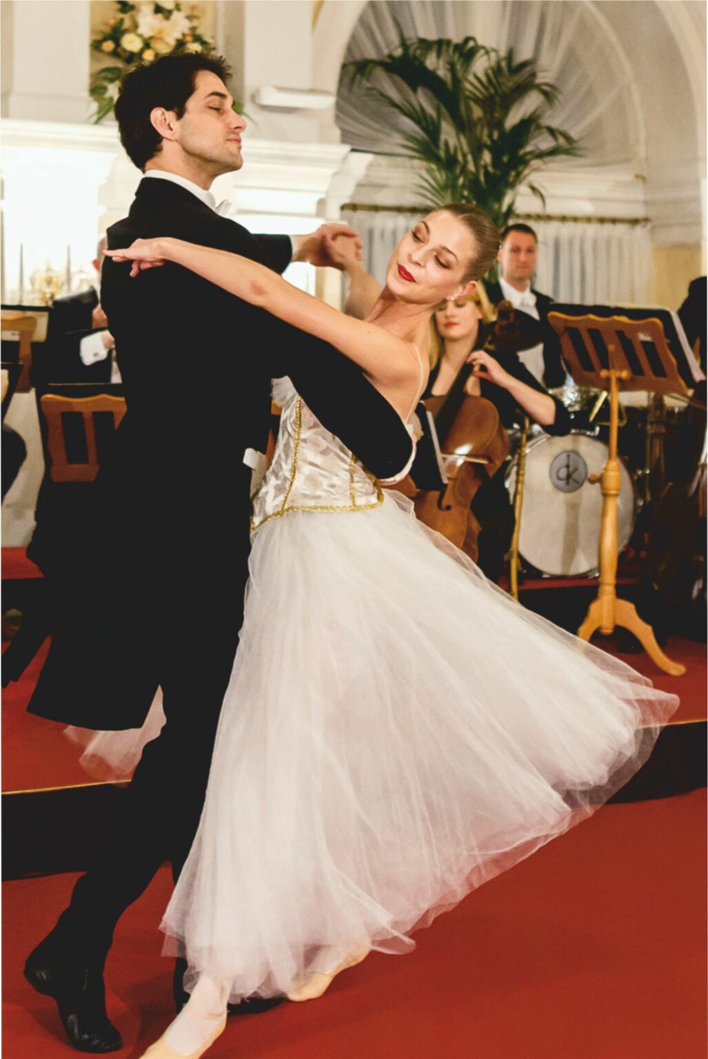 A couple performing a ballroom dance in front of a live orchestra