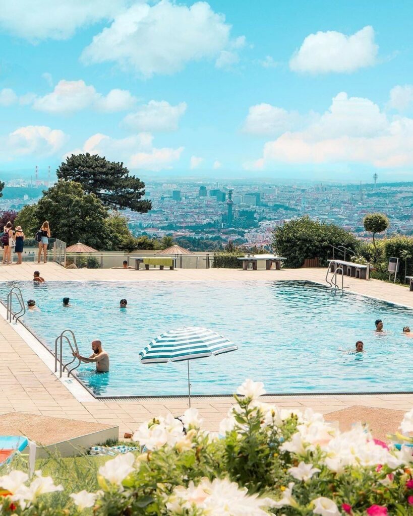 Schwimmbad des Krapfenwaldbads an einem sonnigen Tag mit Blick über Wien